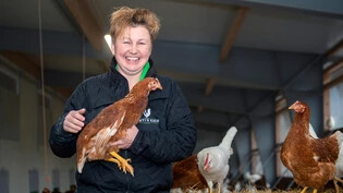 Anhängliche Nutztiere: Gabi Rusterholz posiert im Wintergarten des Familienbetriebs Rusti`s Eier in Cazis mit einem ihrer Hühner auf dem Arm. 