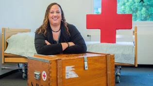 Zelebriert das Jubiläum des Lehrgangs für Pflegehelfende: Livia Umiker posiert mit Requisiten des Schweizerischen Roten Kreuzes in einem Kursraum in der Wiesentalstrasse in Chur. 